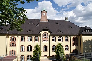 Ein Bild des pastellgelb-gestrichenen Schulhauses.